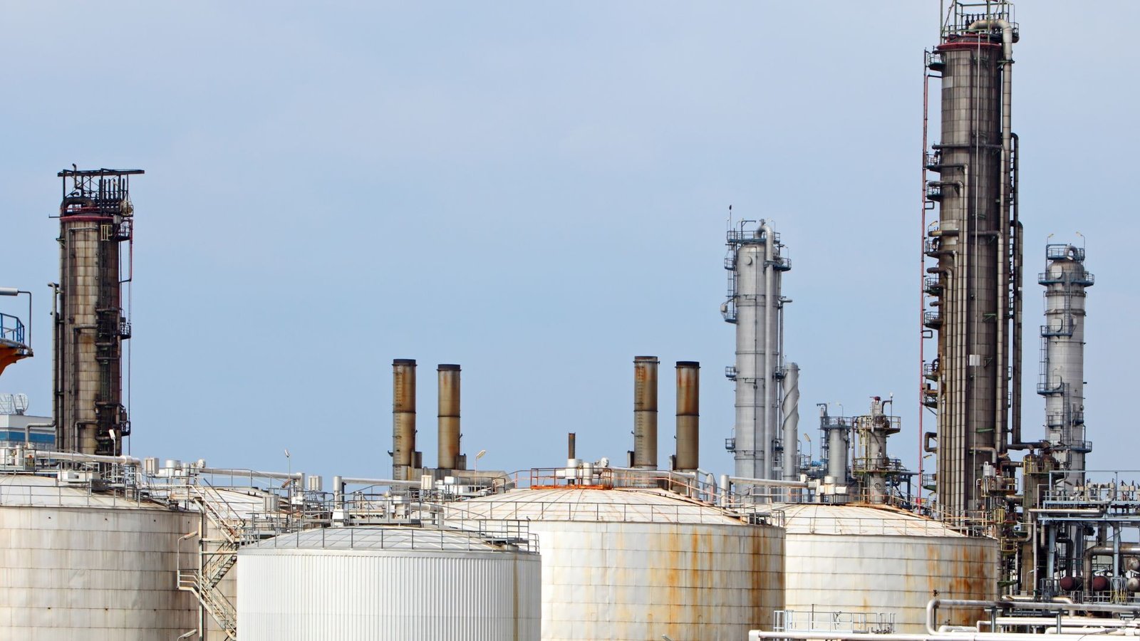 Large petroleum storage tanks with process towers at an industrial refinery.